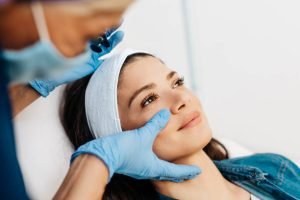 Attractive young woman is getting a rejuvenating facial injections at beauty clinic. The expert beautician is filling female wrinkles by botulinum.